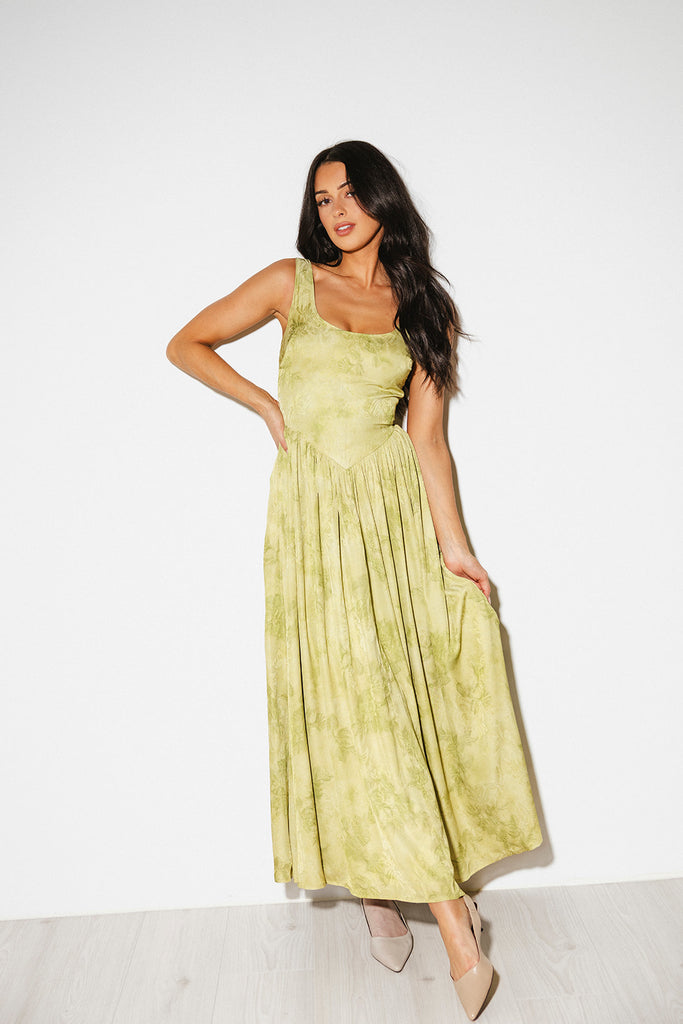 a flowy v-waist green dress with a sleek scoop neckline + subtle floral print. the perfect vintage-inspired maxi dress for weddings, bridal showers, + garden parties.