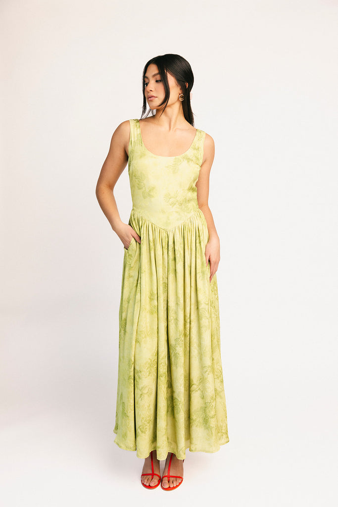 a flowy v-waist green dress with a sleek scoop neckline + subtle floral print. the perfect vintage-inspired maxi dress for weddings, bridal showers, + garden parties.