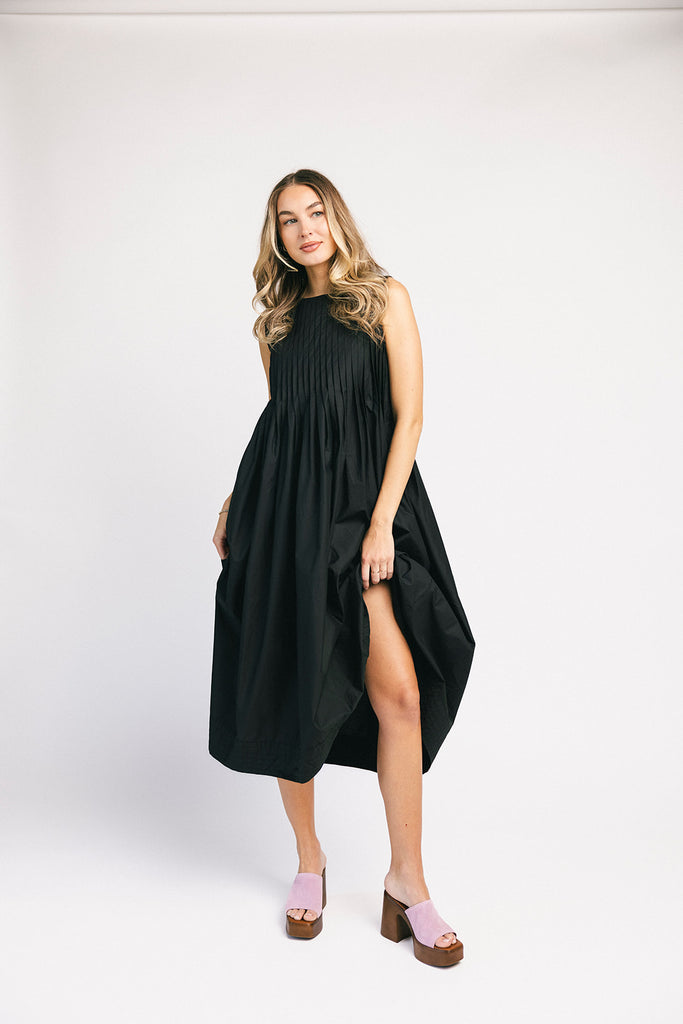 a sleeveless black midi dress with pleated details. the perfect cotton tank dress for weddings, baby showers, brunch dates, + casual outings.