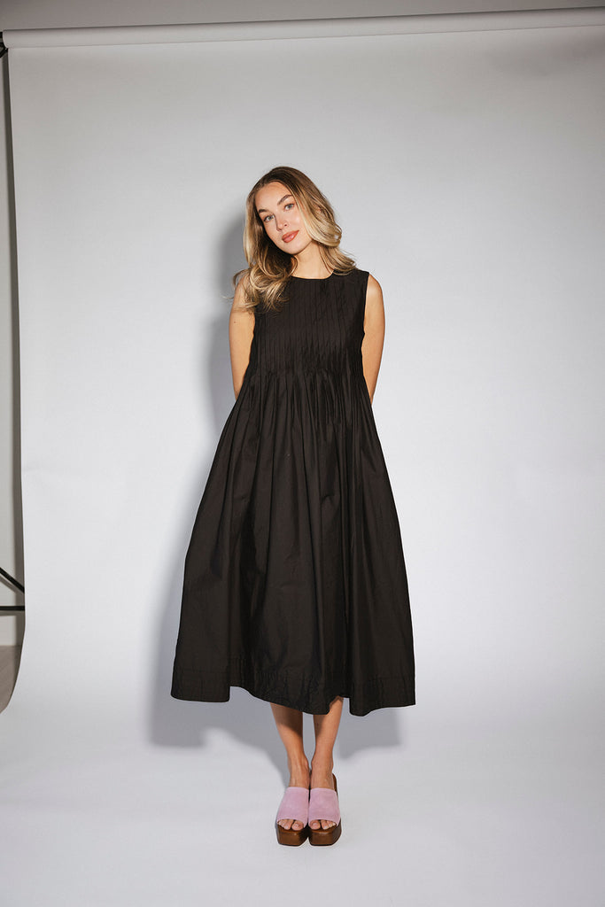 a sleeveless black midi dress with pleated details. the perfect cotton tank dress for weddings, baby showers, brunch dates, + casual outings.