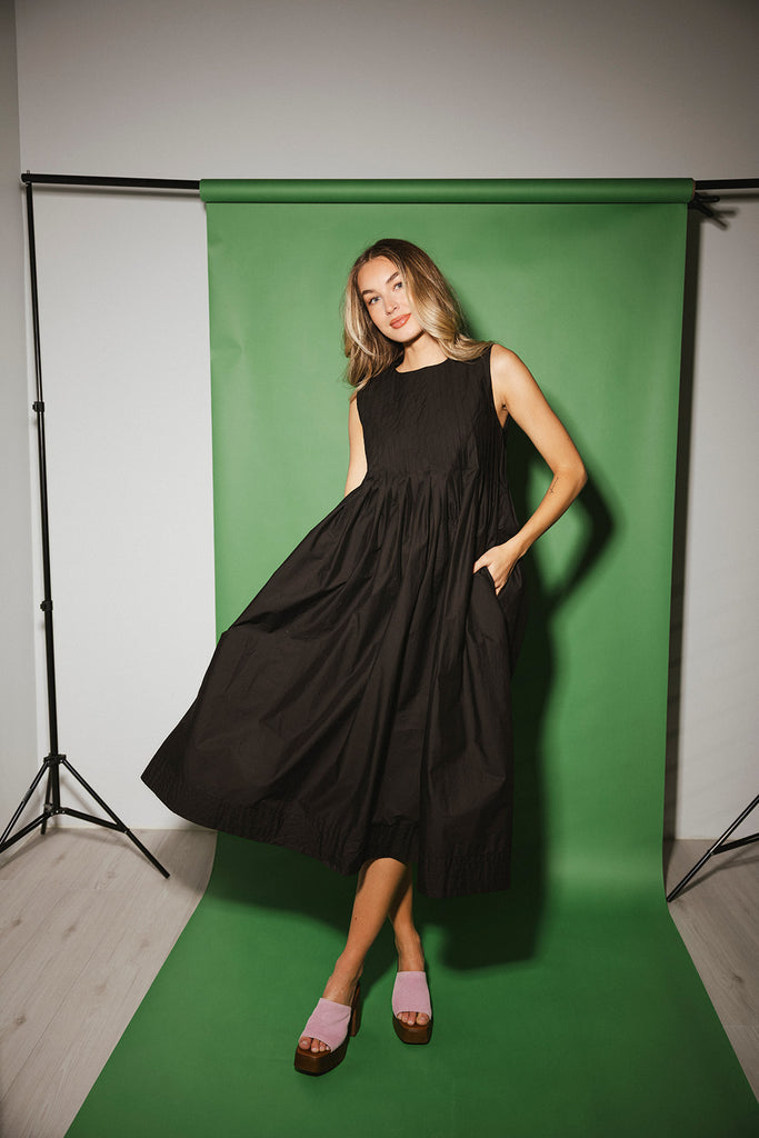 a sleeveless black midi dress with pleated details. the perfect cotton tank dress for weddings, baby showers, brunch dates, + casual outings.