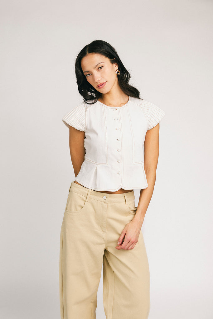 a white denim short sleeve top with a fitted silhouette + a peplum hemline. the perfect denim top to dress up or down for any outfit idea.