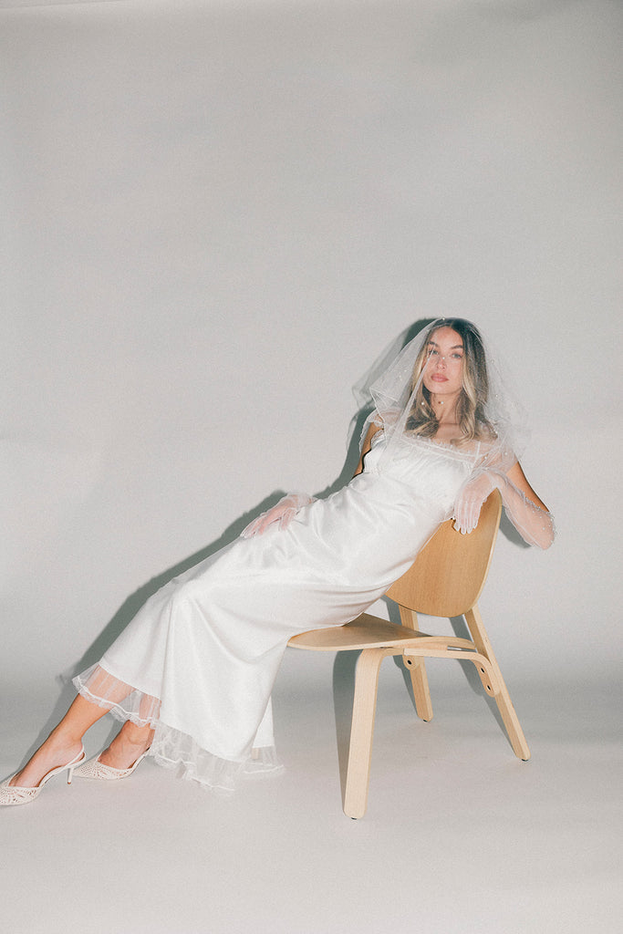 a white satin midi dress with lace detailing + a fitted silhouette. the perfect short sleeve occasion dress for weddings, bridal showers, + dinner parties.