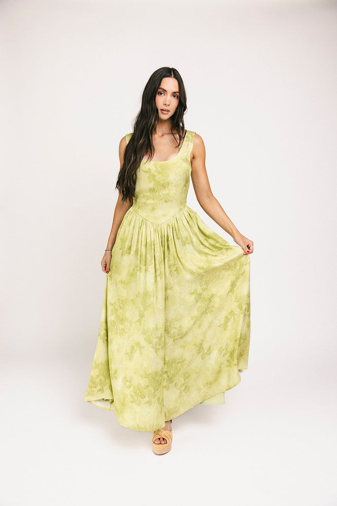 a flowy v-waist green dress with a sleek scoop neckline + subtle floral print. the perfect vintage-inspired maxi dress for weddings, bridal showers, + garden parties.