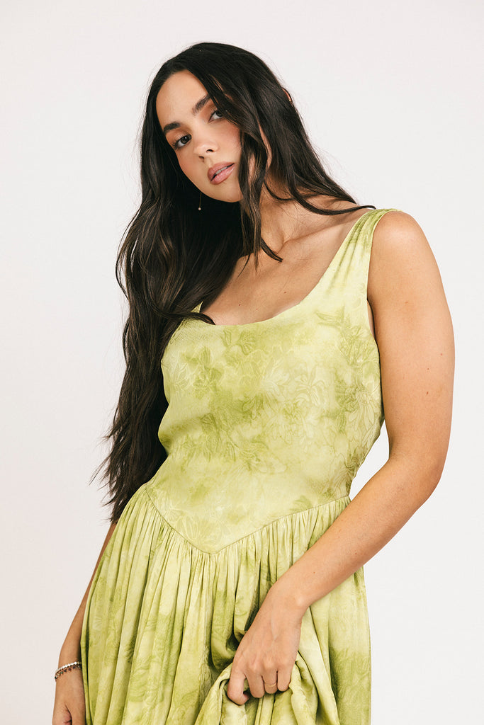 a flowy v-waist green dress with a sleek scoop neckline + subtle floral print. the perfect vintage-inspired maxi dress for weddings, bridal showers, + garden parties.