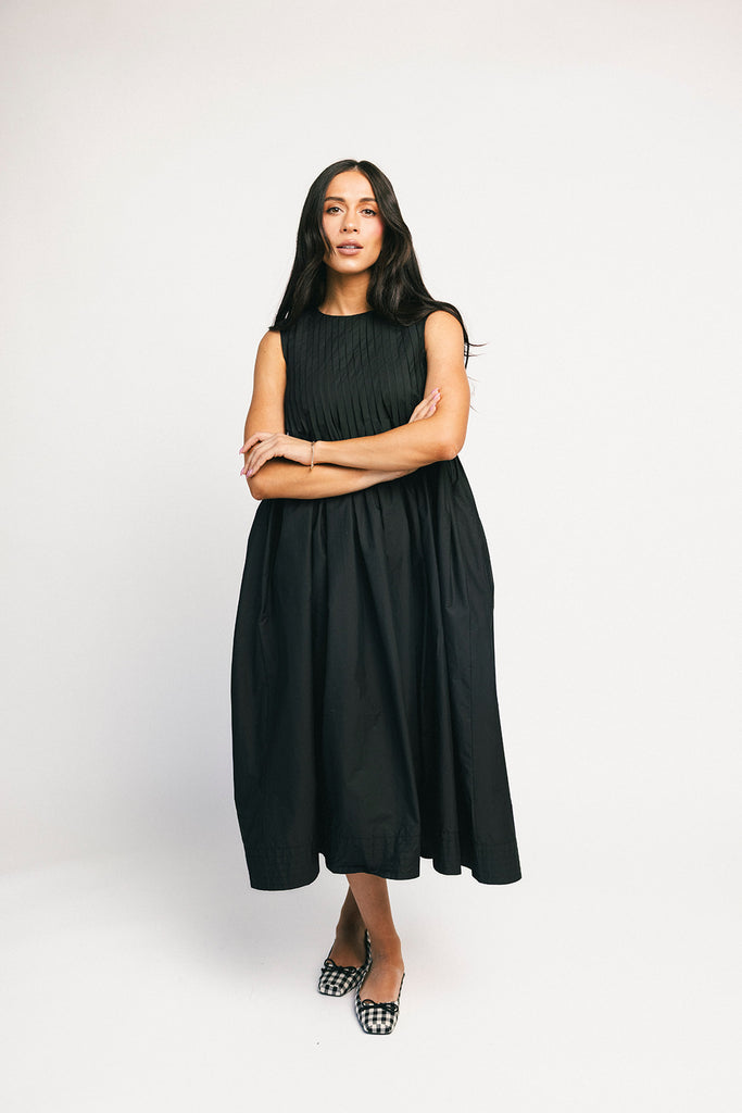 a sleeveless black midi dress with pleated details. the perfect cotton tank dress for weddings, baby showers, brunch dates, + casual outings.