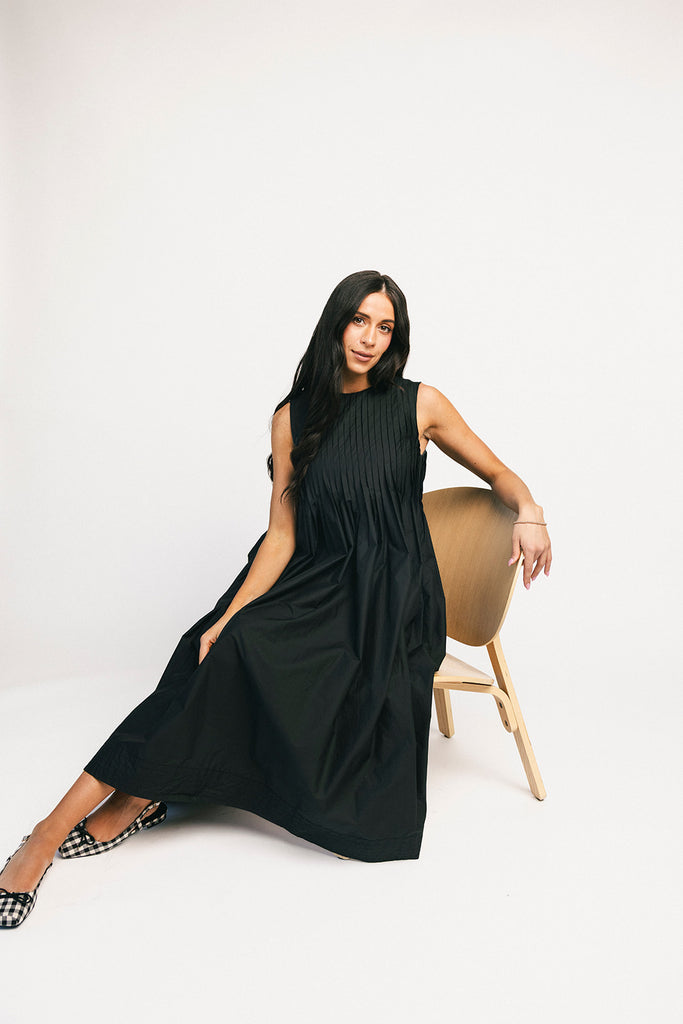 a sleeveless black midi dress with pleated details. the perfect cotton tank dress for weddings, baby showers, brunch dates, + casual outings.