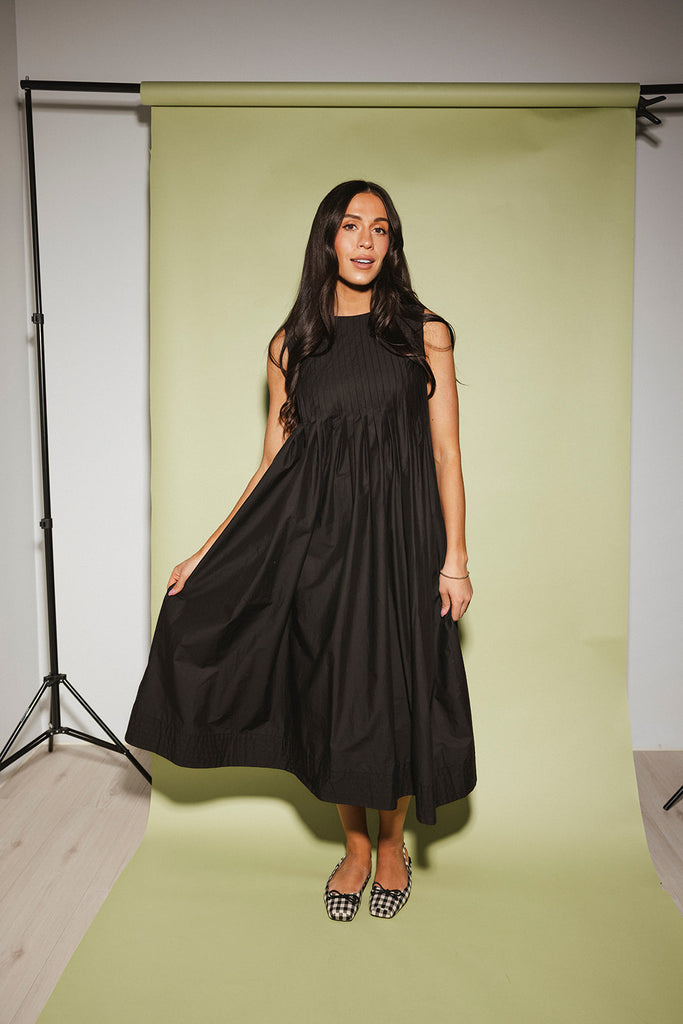 a sleeveless black midi dress with pleated details. the perfect cotton tank dress for weddings, baby showers, brunch dates, + casual outings.