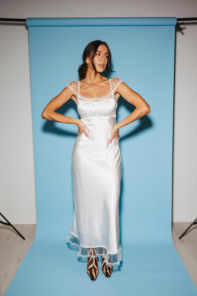a white satin midi dress with lace detailing + a fitted silhouette. the perfect short sleeve occasion dress for weddings, bridal showers, + dinner parties.