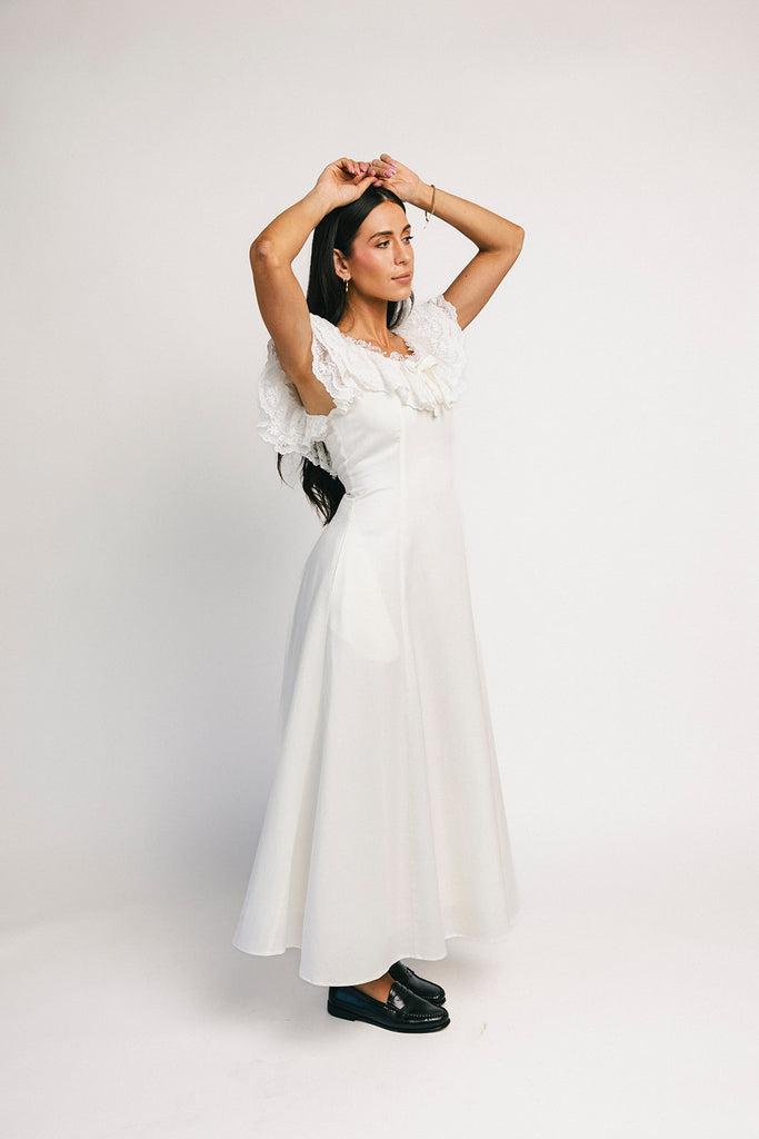 a white vintage-inspired midi dress with a lace ruffle neckline + bow detail. the perfect white dress for bridal showers, rehearsal dinners, + any special occasion.