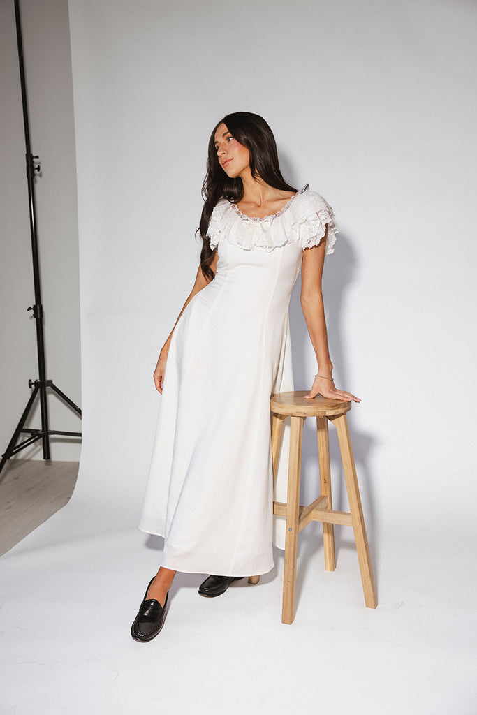 a white vintage-inspired midi dress with a lace ruffle neckline + bow detail. the perfect white dress for bridal showers, rehearsal dinners, + any special occasion.