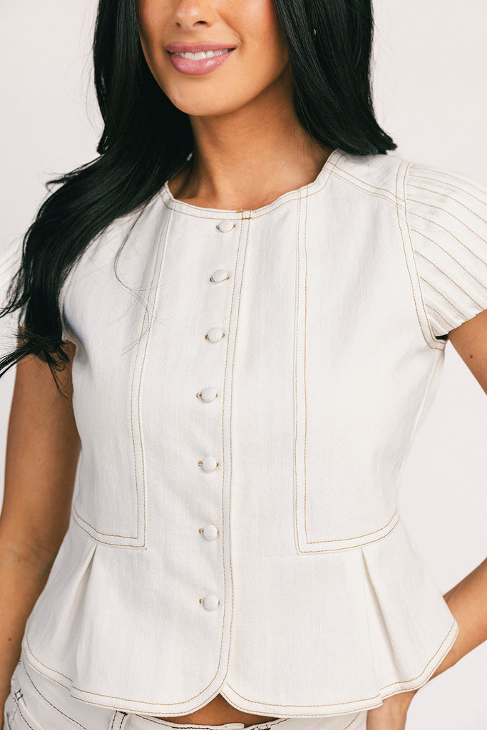 a white denim short sleeve top with a fitted silhouette + a peplum hemline. the perfect denim top to dress up or down for any outfit idea.