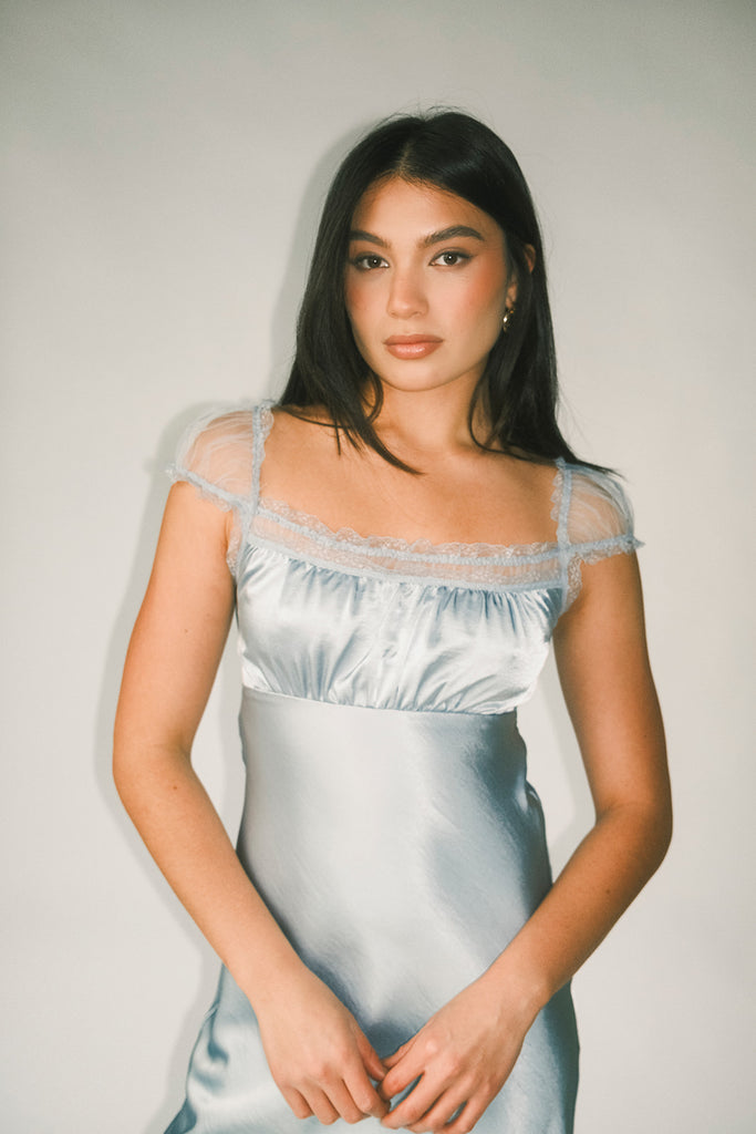 a light blue silk midi dress with lace detailing + a fitted silhouette. the perfect short sleeve occasion dress for weddings, bridal showers, + dinner parties.