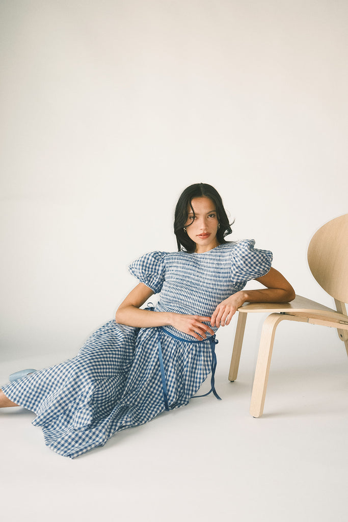 a puff sleeve blue gingham dress with a smocked bodice + side tie details. the perfect vintage-inspired dress for family pictures, weddings, + special occasions.