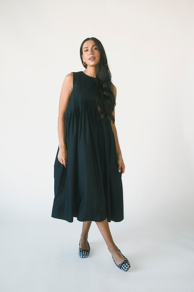 a sleeveless black midi dress with pleated details. the perfect cotton tank dress for weddings, baby showers, brunch dates, + casual outings.
