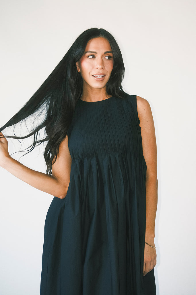 a sleeveless black midi dress with pleated details. the perfect cotton tank dress for weddings, baby showers, brunch dates, + casual outings.