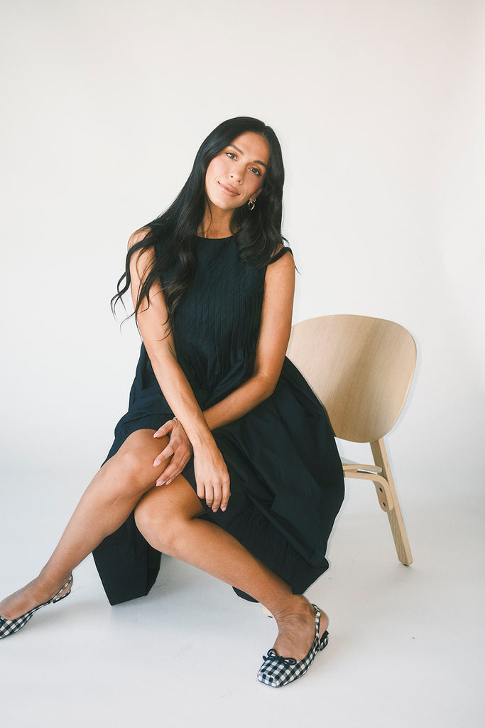 a sleeveless black midi dress with pleated details. the perfect cotton tank dress for weddings, baby showers, brunch dates, + casual outings.