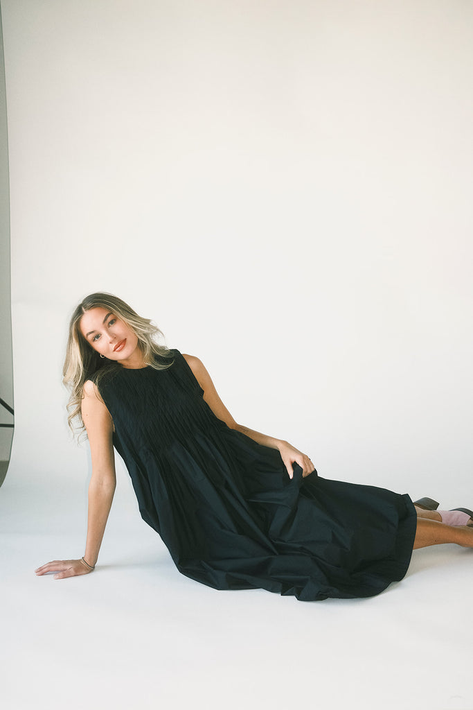 a sleeveless black midi dress with pleated details. the perfect cotton tank dress for weddings, baby showers, brunch dates, + casual outings.