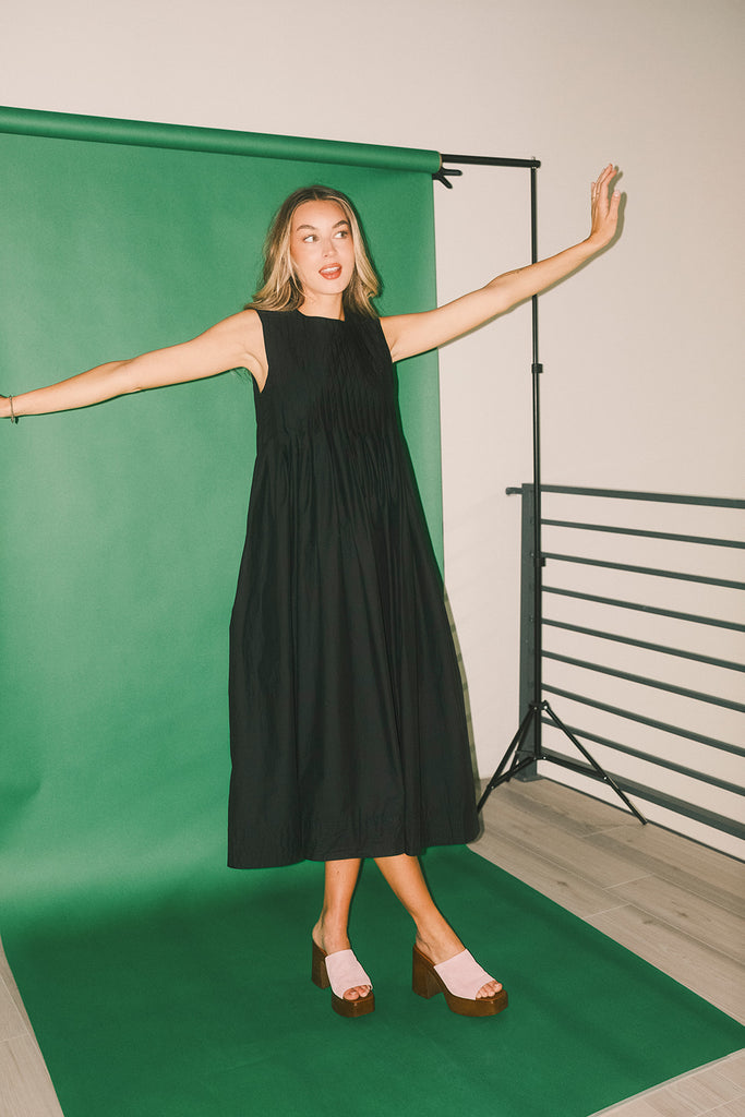 a sleeveless black midi dress with pleated details. the perfect cotton tank dress for weddings, baby showers, brunch dates, + casual outings.