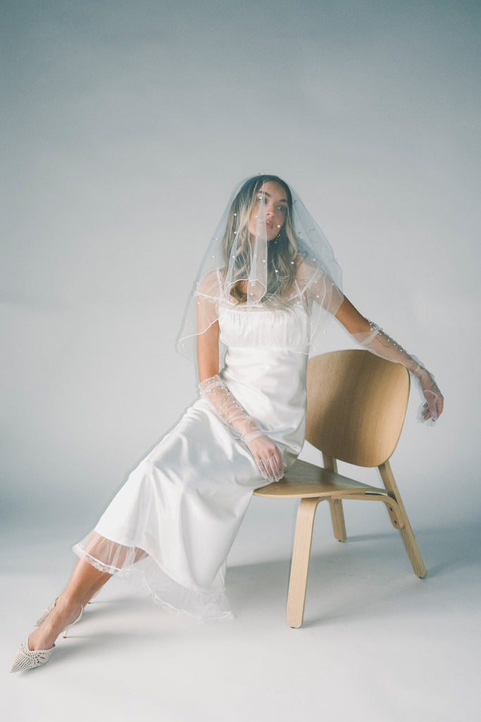 a white satin midi dress with lace detailing + a fitted silhouette. the perfect short sleeve occasion dress for weddings, bridal showers, + dinner parties.