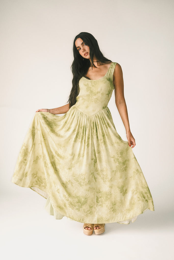 a flowy v-waist green dress with a sleek scoop neckline + subtle floral print. the perfect vintage-inspired maxi dress for weddings, bridal showers, + garden parties.
