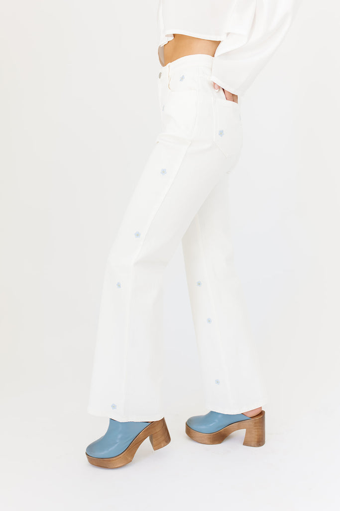 white denim with embroidered daisies, slight flare, one button zipper fly, pockets, and belt loops.