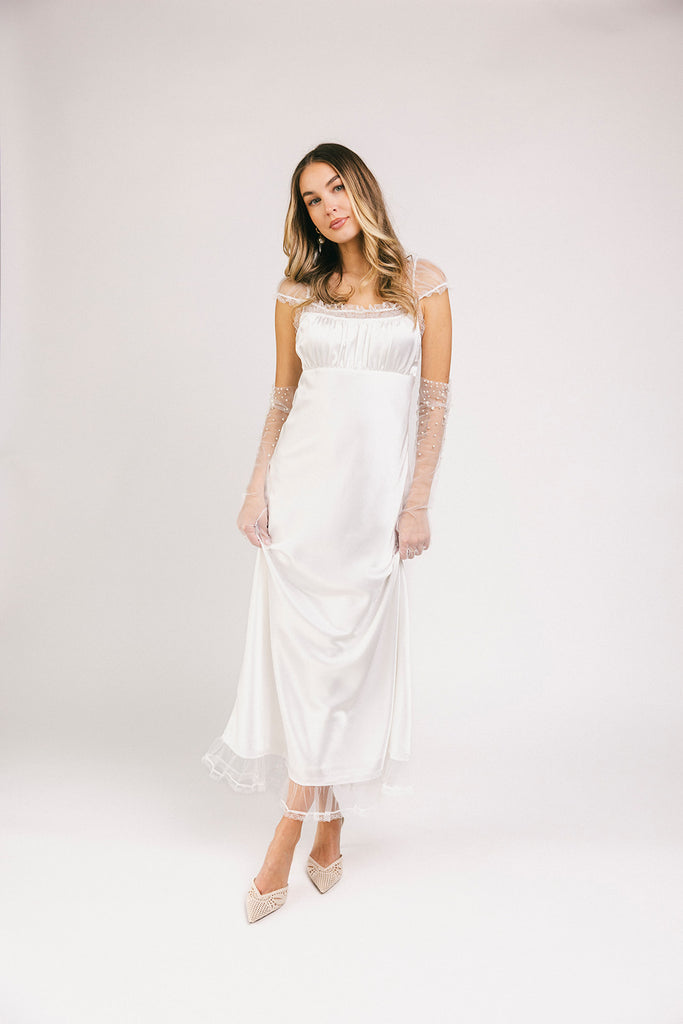 a white satin midi dress with lace detailing + a fitted silhouette. the perfect short sleeve occasion dress for weddings, bridal showers, + dinner parties.
