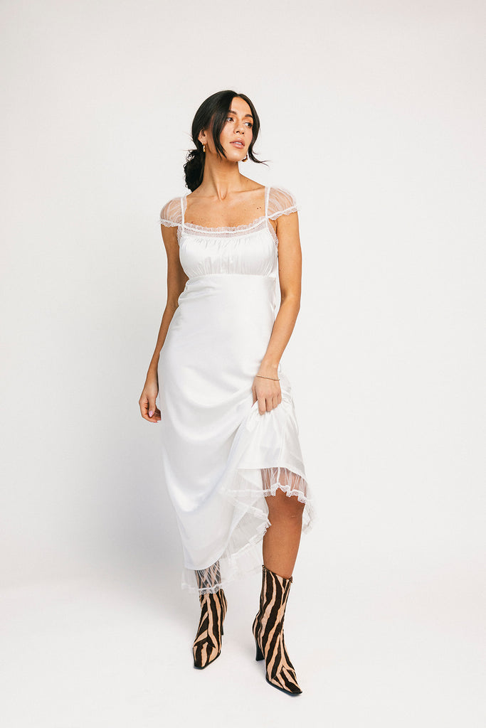 a white satin midi dress with lace detailing + a fitted silhouette. the perfect short sleeve occasion dress for weddings, bridal showers, + dinner parties.
