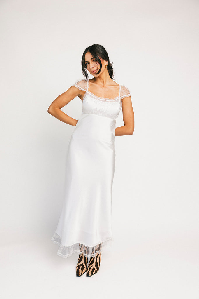 a white satin midi dress with lace detailing + a fitted silhouette. the perfect short sleeve occasion dress for weddings, bridal showers, + dinner parties.
