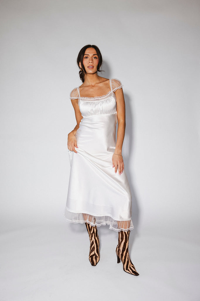 a white satin midi dress with lace detailing + a fitted silhouette. the perfect short sleeve occasion dress for weddings, bridal showers, + dinner parties.