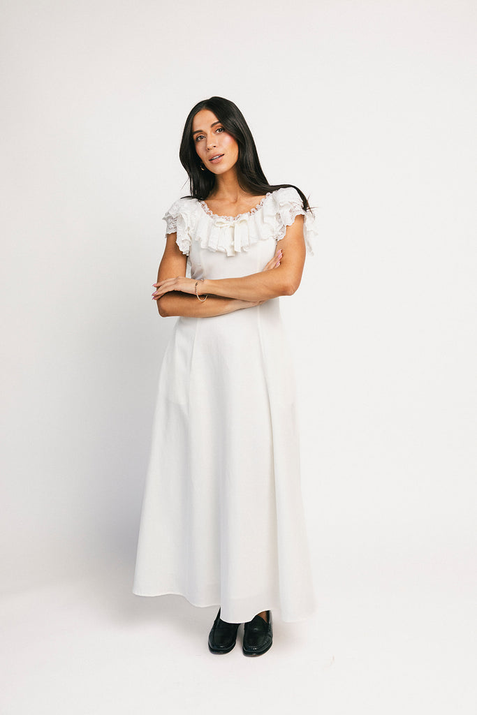 a white vintage-inspired midi dress with a lace ruffle neckline + bow detail. the perfect white dress for bridal showers, rehearsal dinners, + any special occasion.
