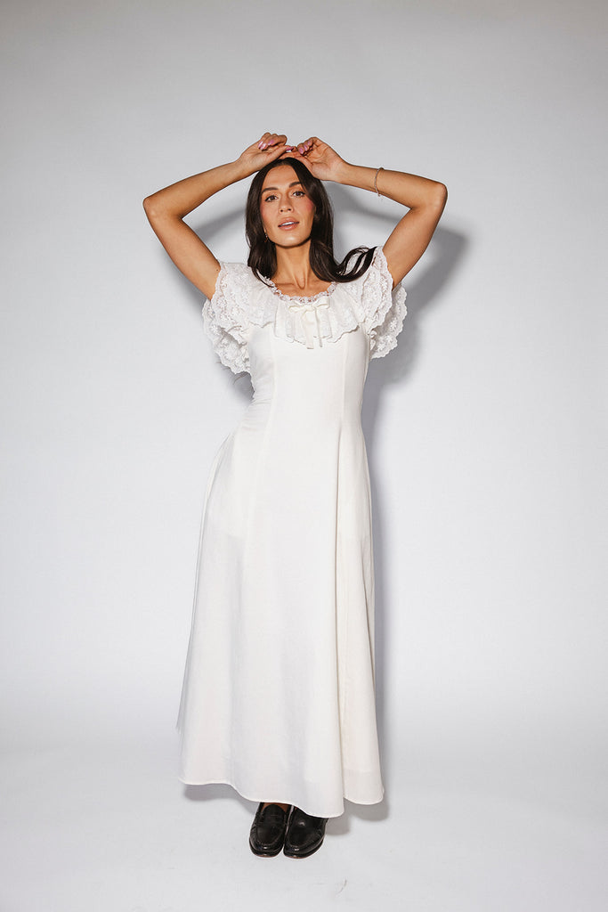 a white vintage-inspired midi dress with a lace ruffle neckline + bow detail. the perfect white dress for bridal showers, rehearsal dinners, + any special occasion.
