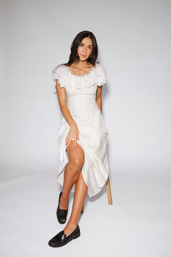 a white vintage-inspired midi dress with a lace ruffle neckline + bow detail. the perfect white dress for bridal showers, rehearsal dinners, + any special occasion.
