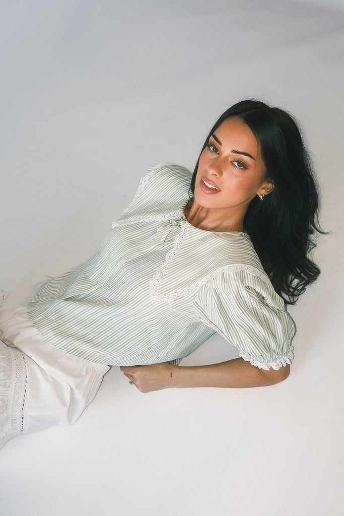 a vintage-inspired puff sleeve top with a pastel green pinstripe pattern + an oversized lace trim collar. the perfect elevated button up top for the office, dressy date nights, + everyday wear.
