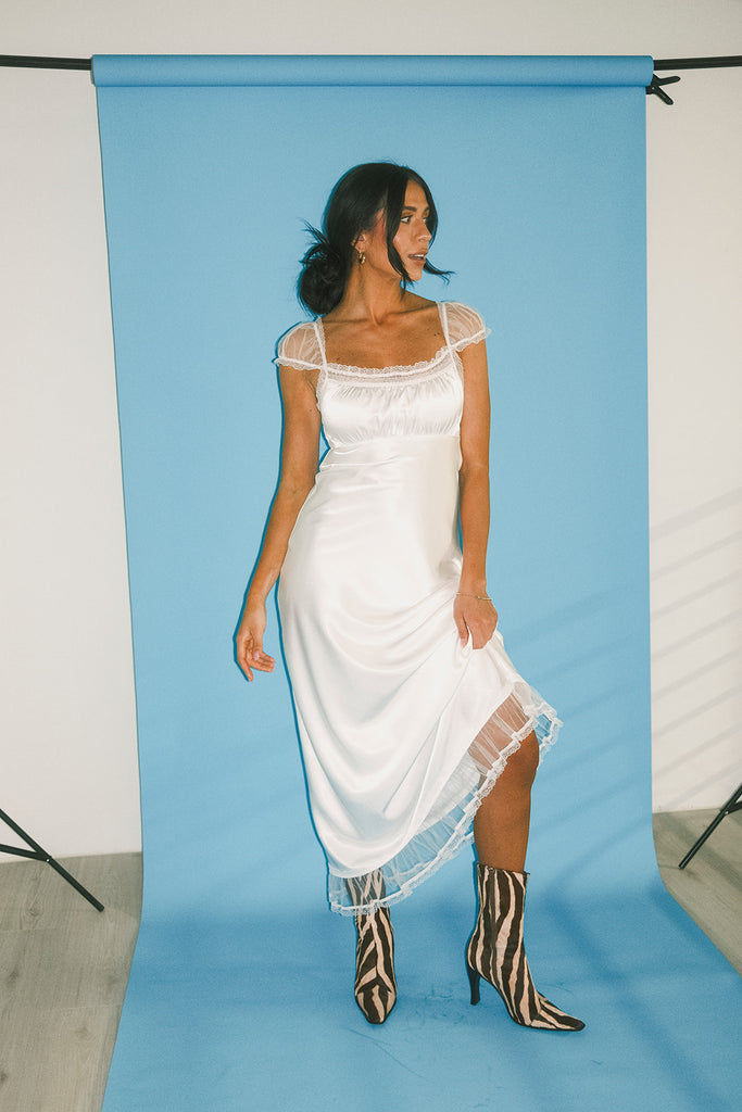 a white satin midi dress with lace detailing + a fitted silhouette. the perfect short sleeve occasion dress for weddings, bridal showers, + dinner parties.
