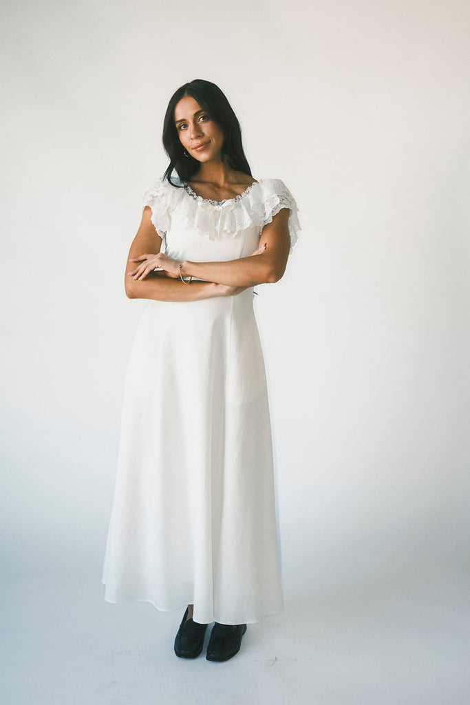 a white vintage-inspired midi dress with a lace ruffle neckline + bow detail. the perfect white dress for bridal showers, rehearsal dinners, + any special occasion.
