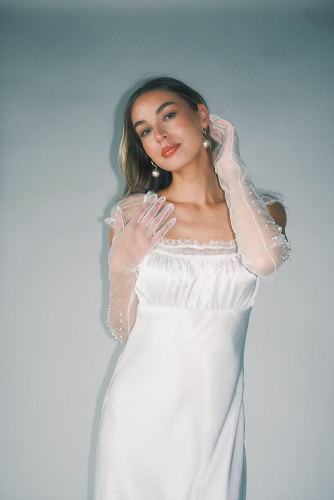a white satin midi dress with lace detailing + a fitted silhouette. the perfect short sleeve occasion dress for weddings, bridal showers, + dinner parties.
