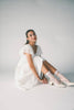 a white vintage-inspired midi dress with a lace ruffle neckline + bow detail. the perfect white dress for bridal showers, rehearsal dinners, + any special occasion.

