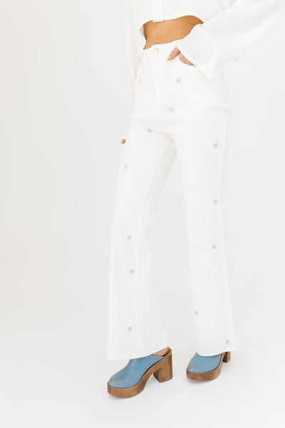 white denim with embroidered daisies, slight flare, one button zipper fly, pockets, and belt loops.