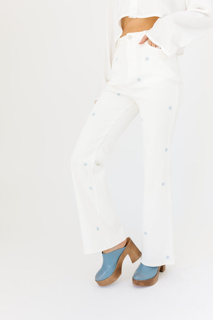 white denim with embroidered daisies, slight flare, one button zipper fly, pockets, and belt loops.