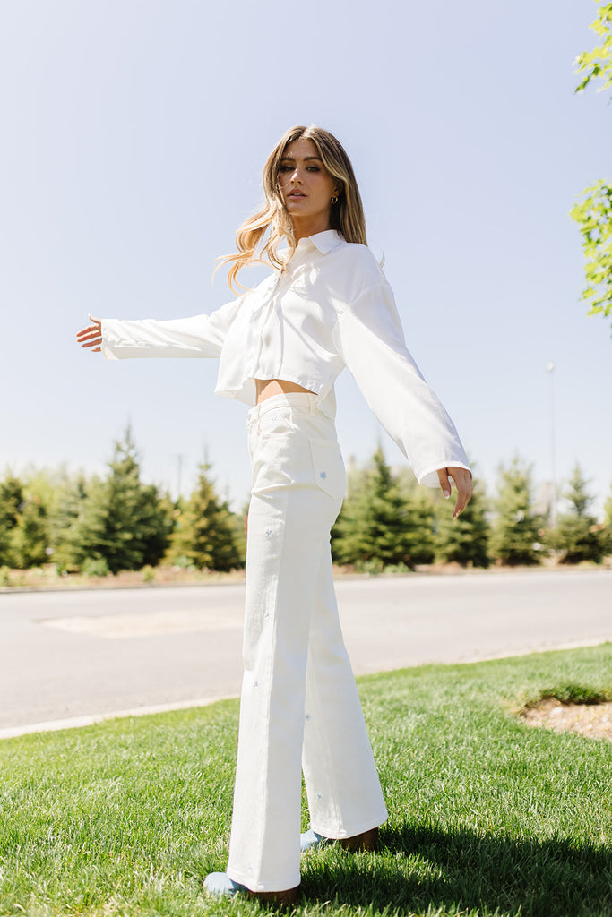 white denim with embroidered daisies, slight flare, one button zipper fly, pockets, and belt loops.